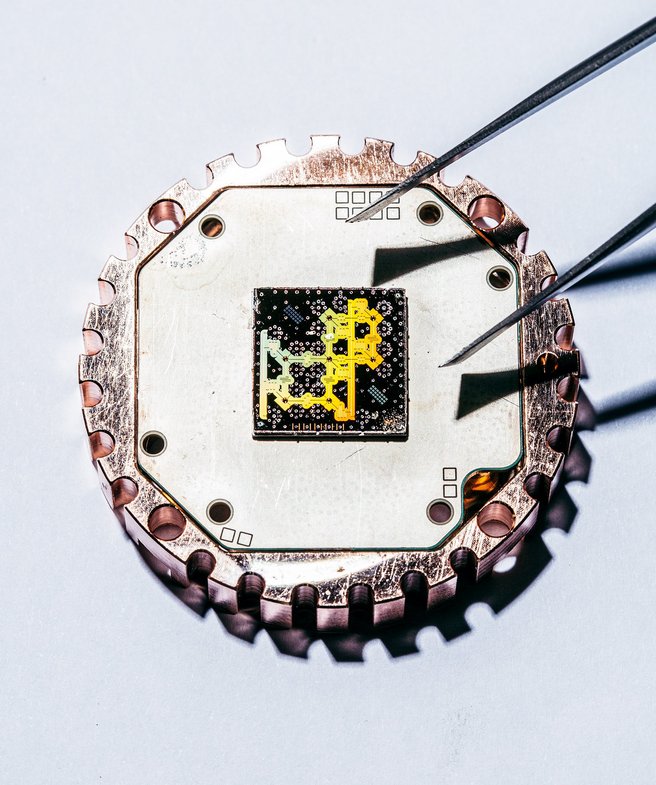 Foto eines Quantenbits, dem sich gerade eine Pinzette nähert. 