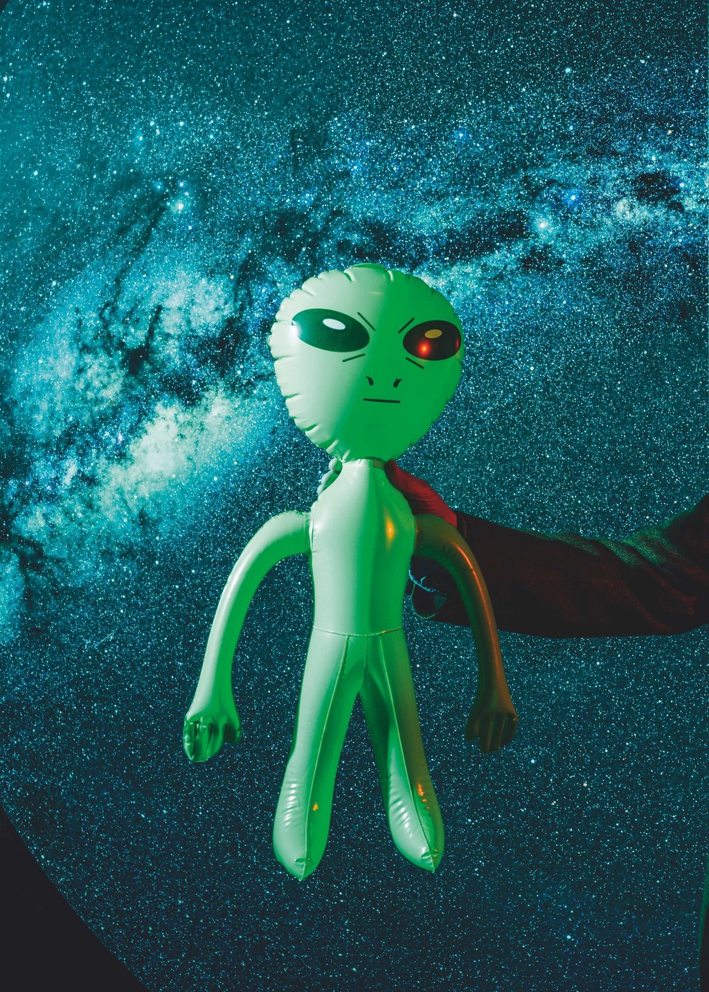 Ein grüner, aufblasbarer Alien vor einem Sternen-Hintergrund.