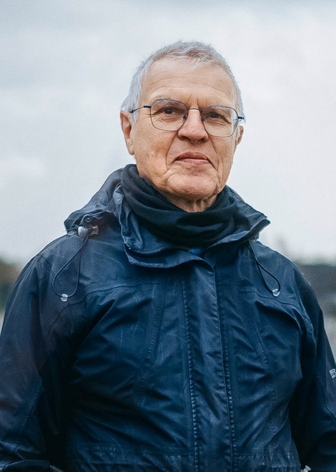 Portait-Foto von Johannes Frech, der aus Brille und einer schwarzen Regenjacke in die Kamera blickt. 