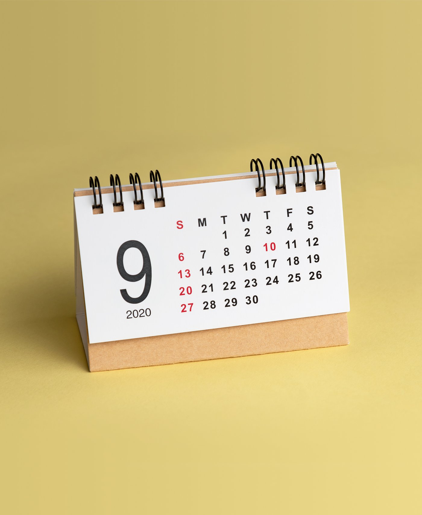 Stehender Kalender mit Monatsansicht September 2020 vor gelbem Hintergrund.